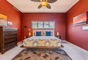 A bedroom with a bed, dresser, window, and artwork. - Puerta Cortés 404 - 2BD Marina View Condo (La Paz)