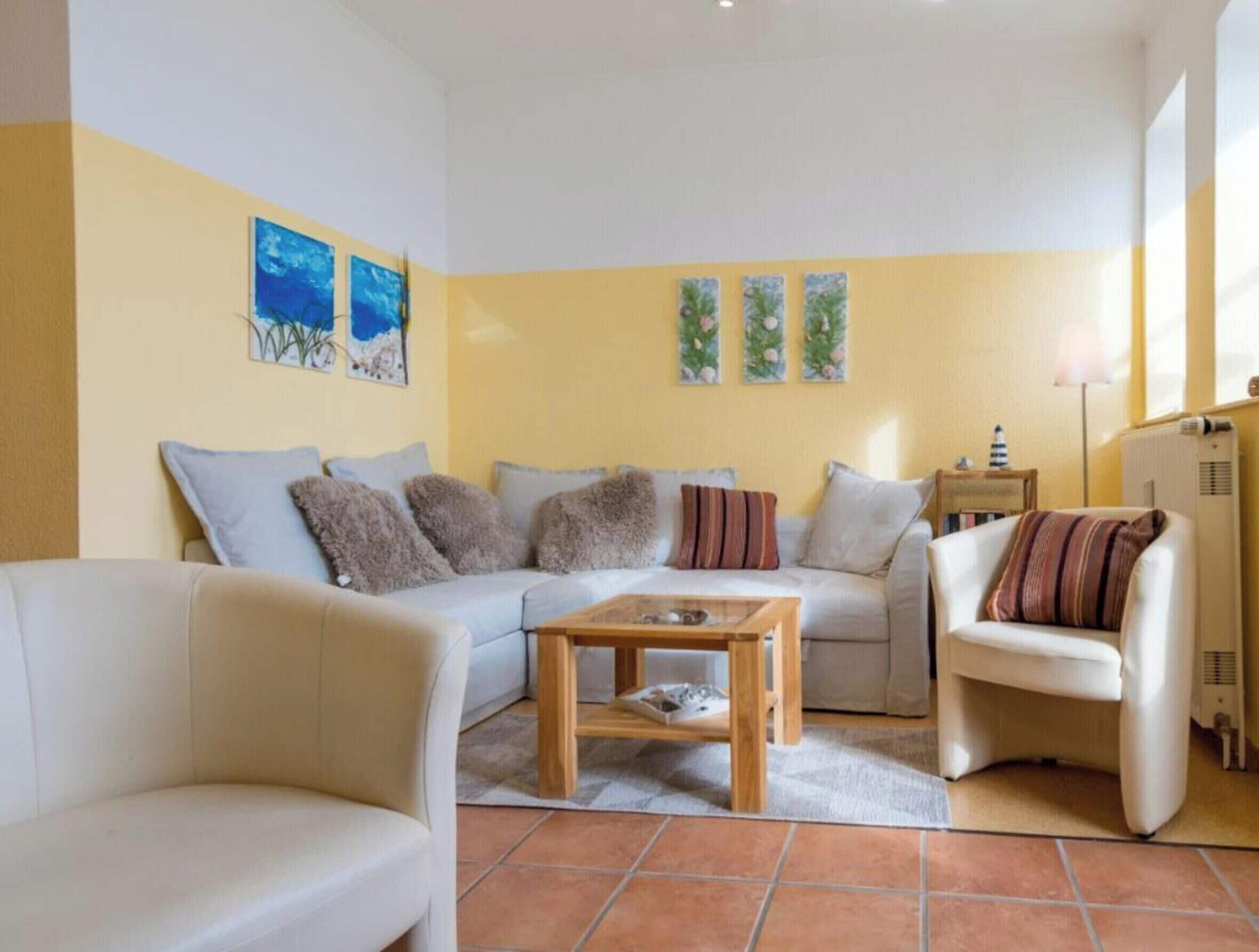 A living room with a sofa, armchairs, a coffee table, and artwork on the walls.