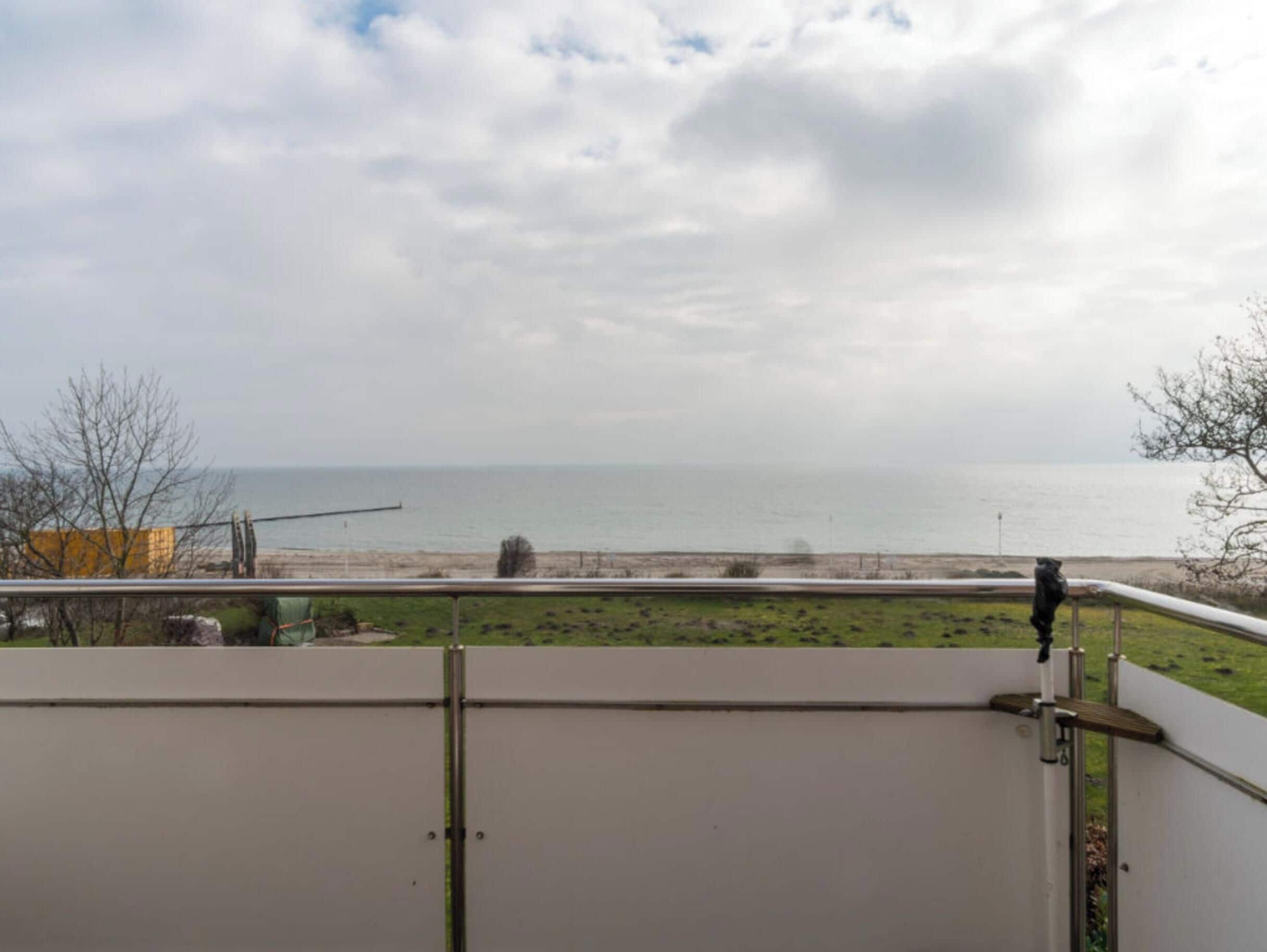 Vistes des d'un balcó sobre una platja sota un cel nuvolós.