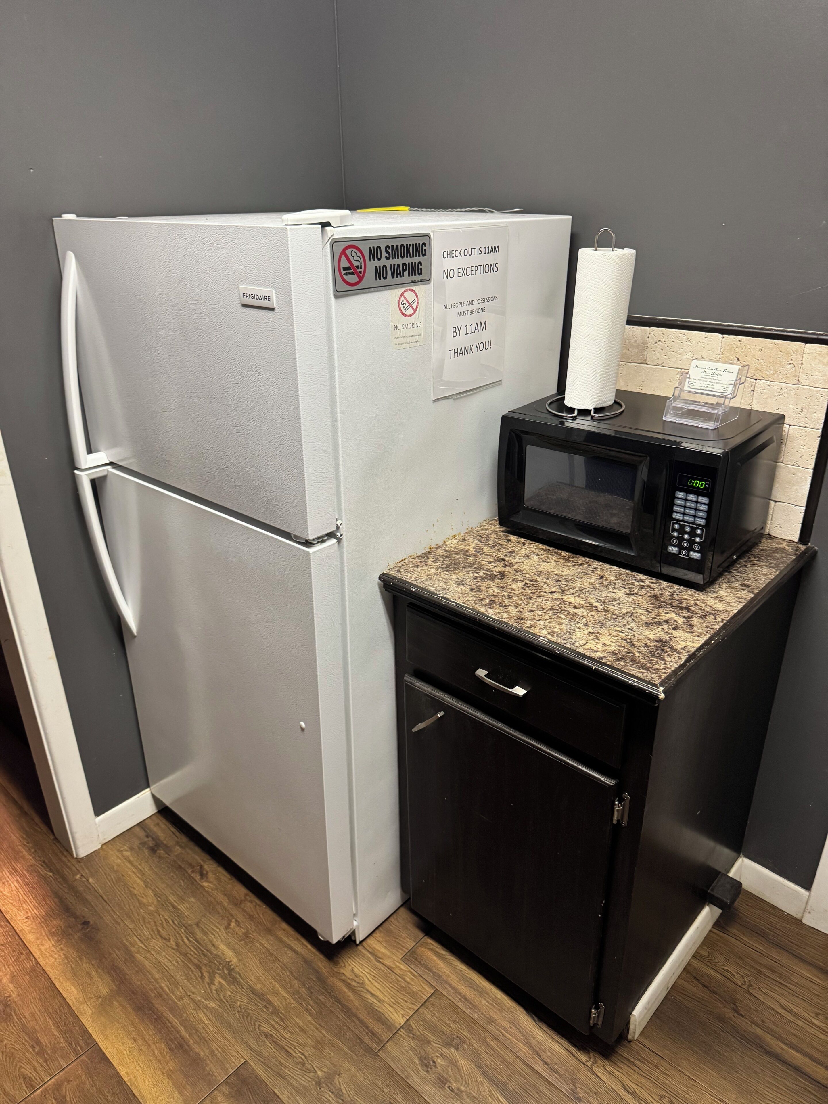 A compact kitchenette with a refrigerator, microwave, and a small cabinet.