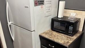 Una kitchenette compacta con refrigerador, microondas y un mueble pequeño.