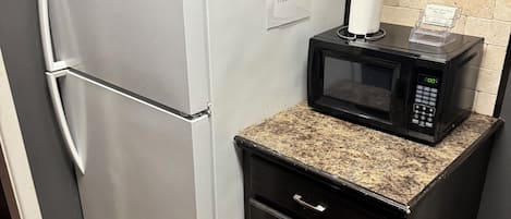 A compact kitchenette with a refrigerator, microwave, and a small cabinet.