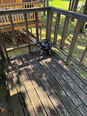 A wooden deck with a barbecue grill.