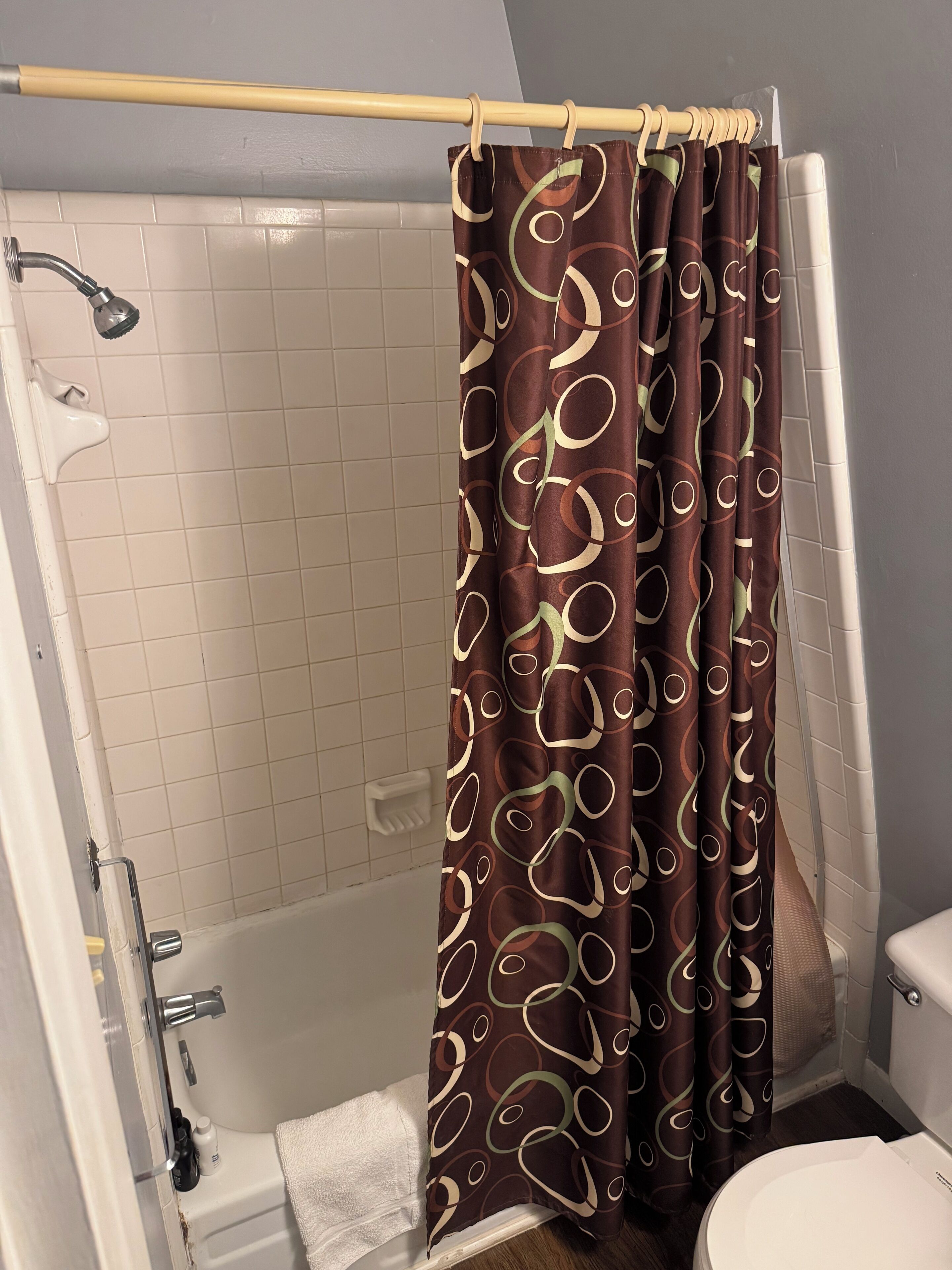 A bathroom with a shower, toilet, and a towel rack.