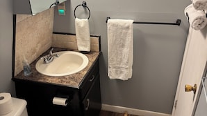 Et badeværelse med vask, toilet og håndklædestige.