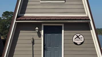 A two-story building with a dark gray siding exterior, a brown roof, and a single door with a window above it.