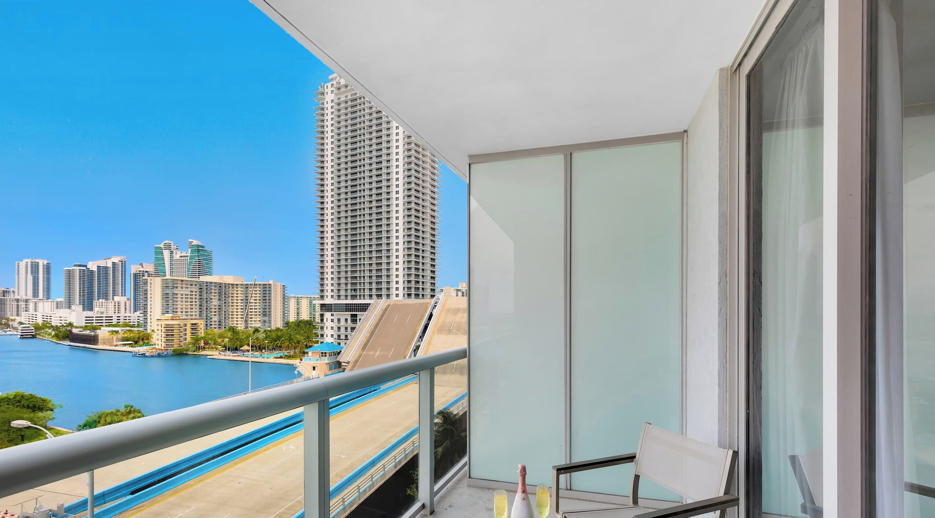 Uma varanda com vista para o horizonte urbano, uma piscina e uma cadeira.
