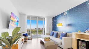 A modern living room with a sofa, coffee table, and a large window. - Marina Front | Modern 2BR APT | Beachwalk Resort (Hallandale Beach)
