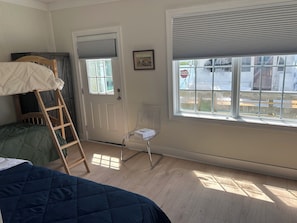A room with a bunk bed, a ladder, a clear chair, a door with a window, and a framed picture on the wall. - Newly rennovated Two bedroom waterfront Get Away. (Morehead City)