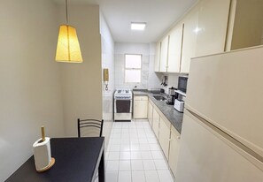 A compact kitchen with a stove, sink, and a dining area with a table and chairs. - Studio Central Located in Recoleta | Av. Santa Fe, universities & health centers (Buenos Aires)
