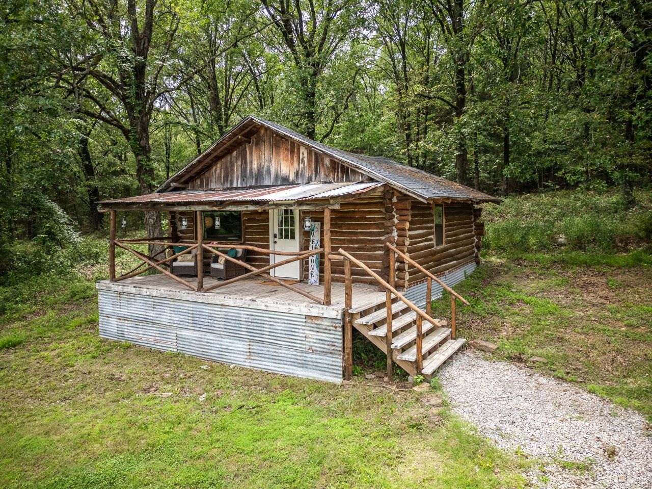Eine rustikale Holzhütte mit Veranda, Holzstufen und einem Kiesweg, der dorthin führt.