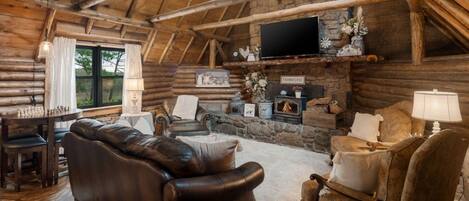 A log cabin interior with a fireplace, leather furniture, and a flat-screen TV.