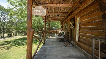 A wooden porch with a sign reading 'The Porch Sit & Relax' and a 'Welcome' sign on the wall.