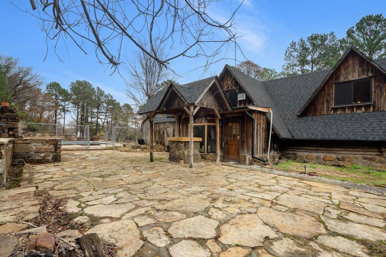 A rustic cabin with a stone patio, wooden exterior, and a covered entryway.