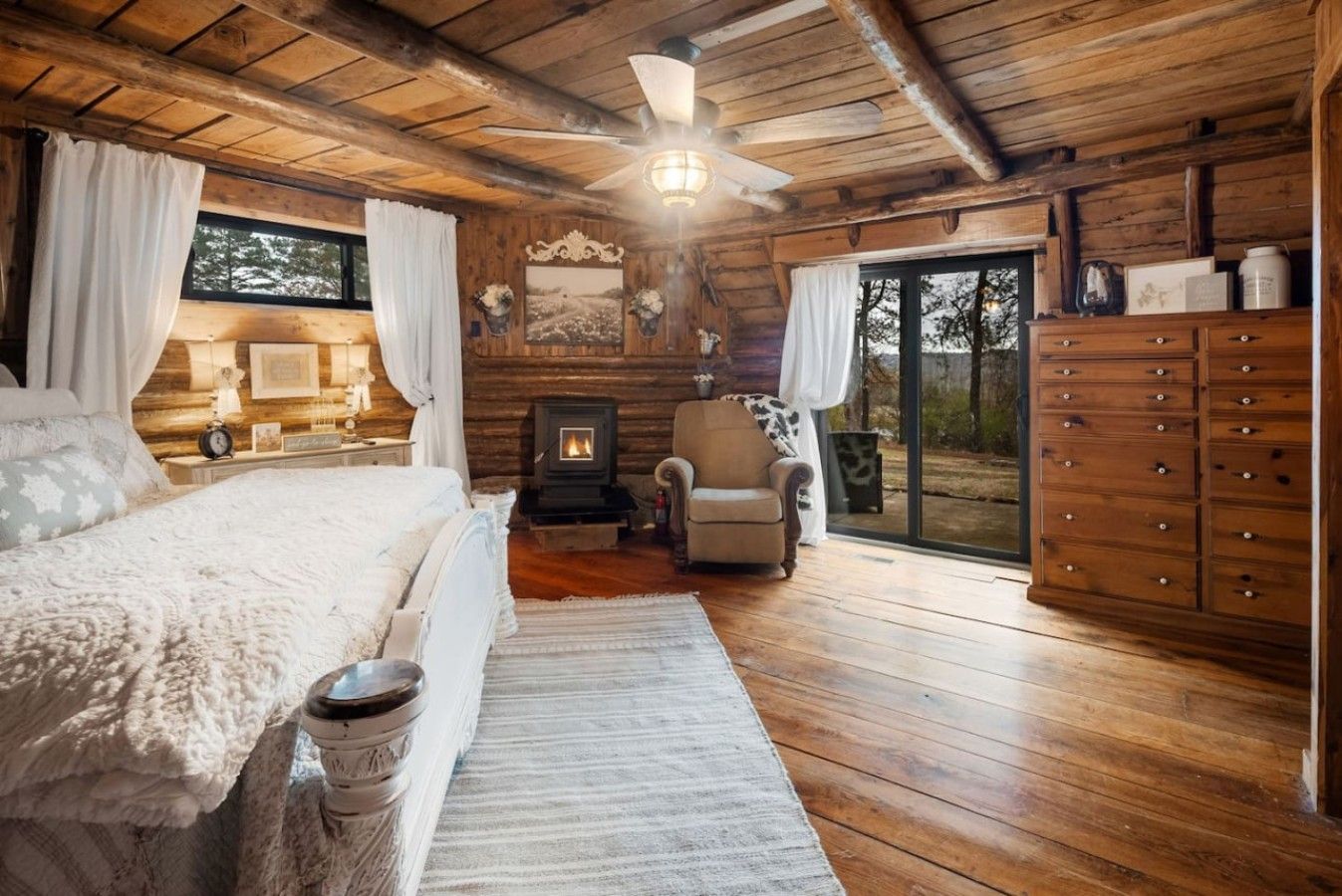 A cozy bedroom with a bed, a chair, a fireplace, and a wardrobe.