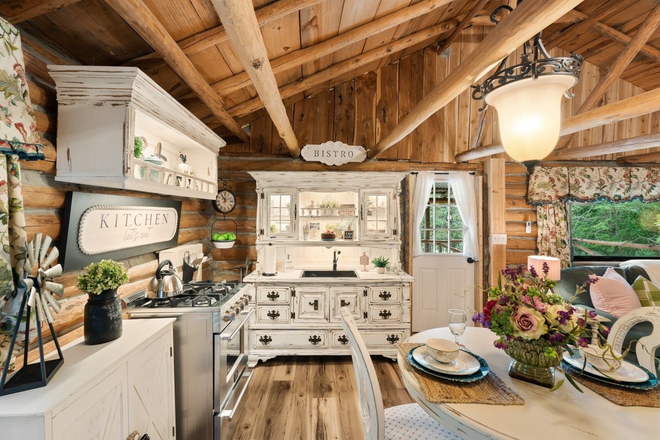 A rustic kitchen with wooden beams, a vintage sink, and a dining area with a table set for two.