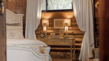 A rustic bedroom with a bed, a dresser, and a window with curtains.