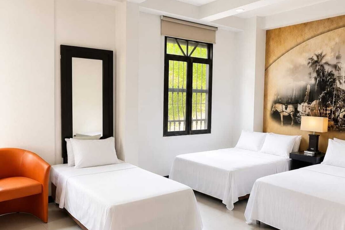 Camera d'albergo con due letti, una poltrona, un quadro e una finestra vista panoramica.