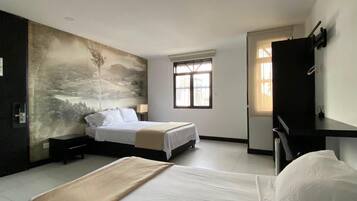 A hotel room with two beds, a large wall mural, a window, and a desk.