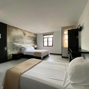Una camera d'albergo con due letti, un grande affresco, una finestra e una scrivania.