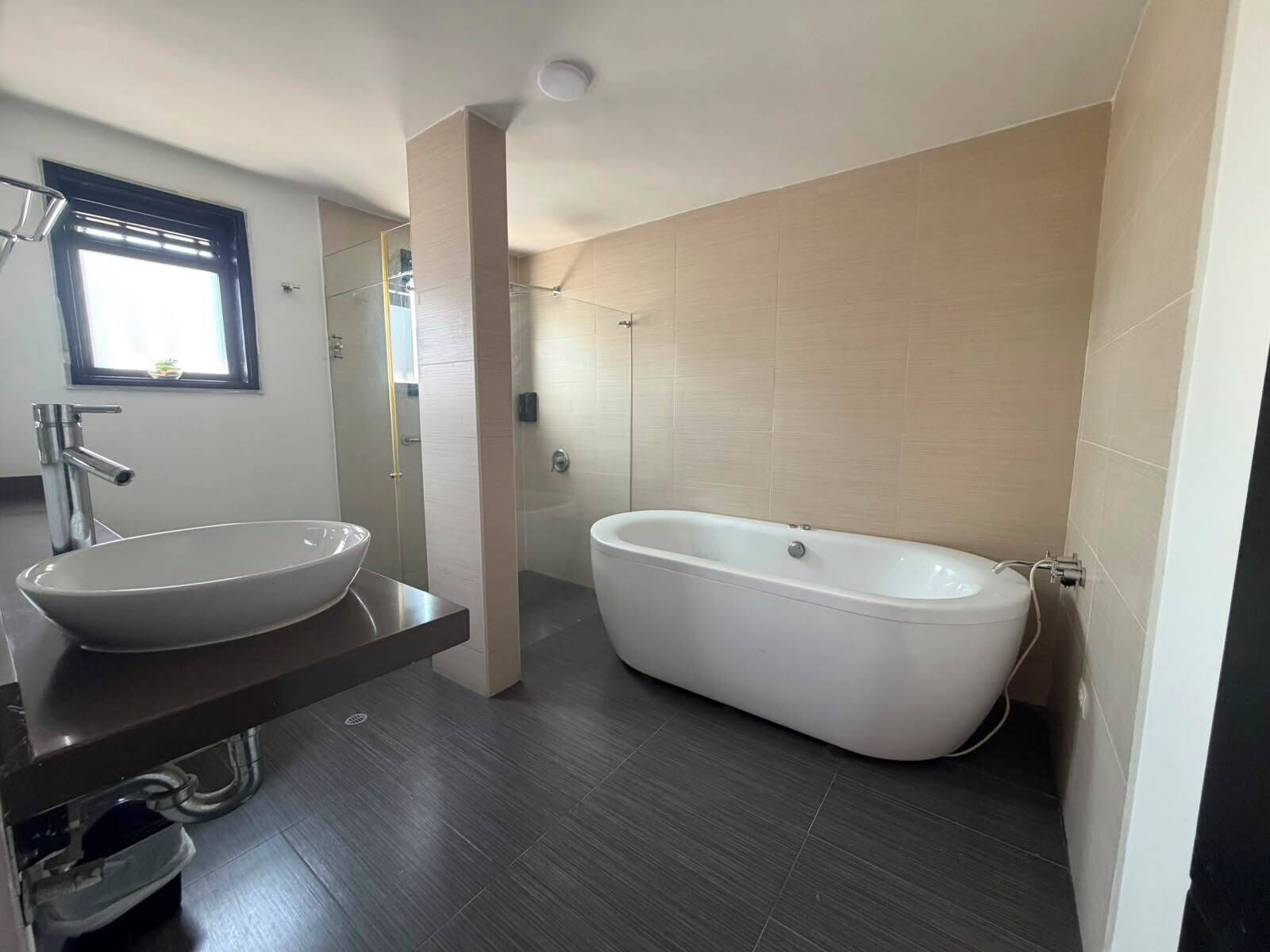 Un baño moderno con una bañera independiente, un lavamanos sobre encimera y una ducha con mampara de vidrio.