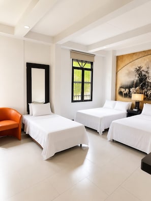 A hotel room with two beds, a chair, a painting, and a window with a view.