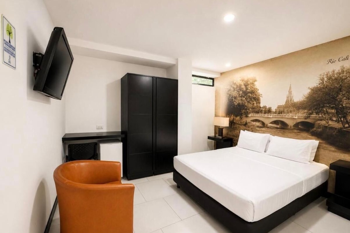 Una camera da letto con un letto, una scrivania, una sedia e un televisore a parete.