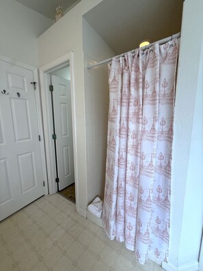 A bathroom with a shower curtain featuring architectural designs, a white door, and a tiled floor. - Tropical Golf Paradise (Haines City)