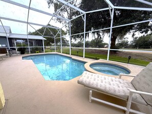 Una piscina con hidromasaje, rodeada por un porche cubierto con sillas.