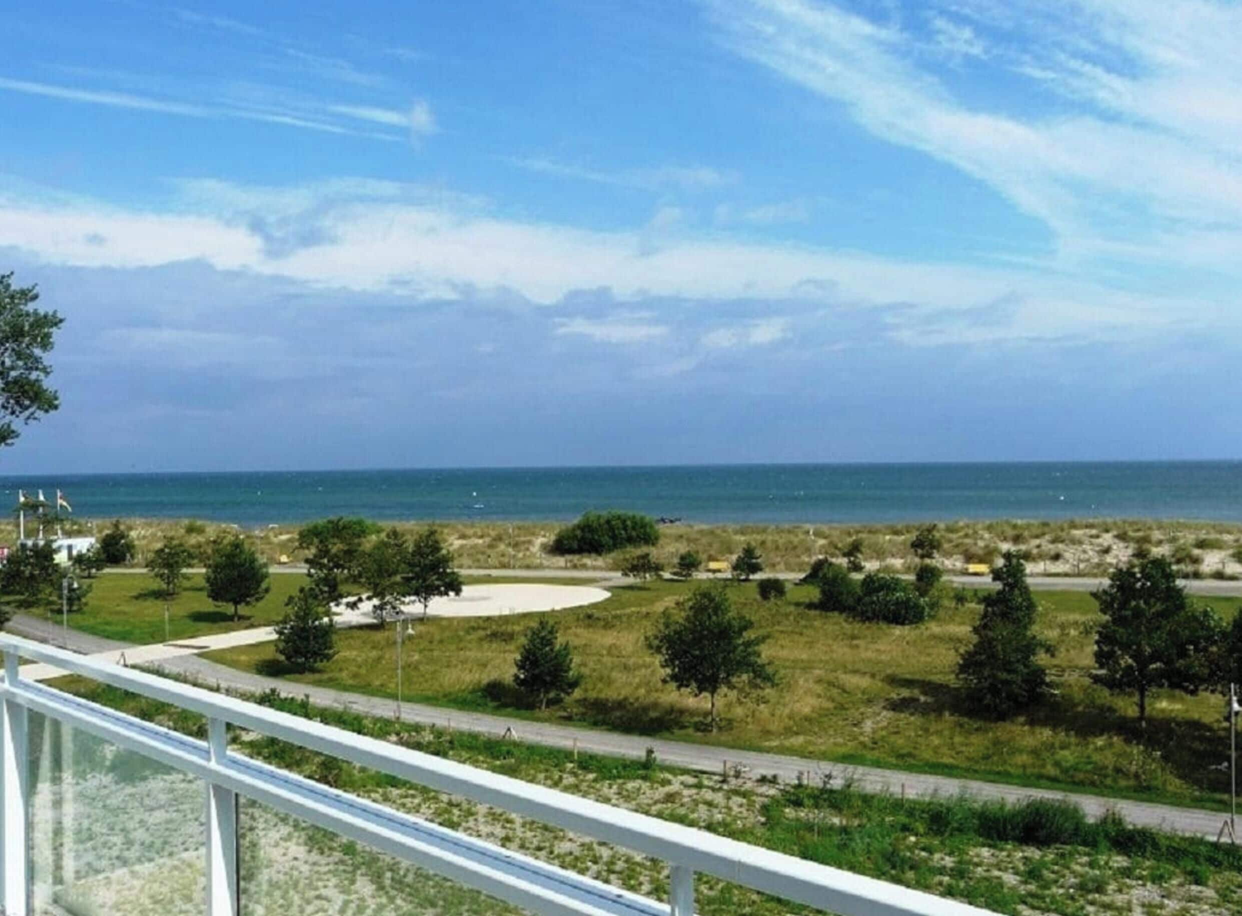 Un paysage côtier avec un ciel dégagé, une zone sablonneuse et une route.