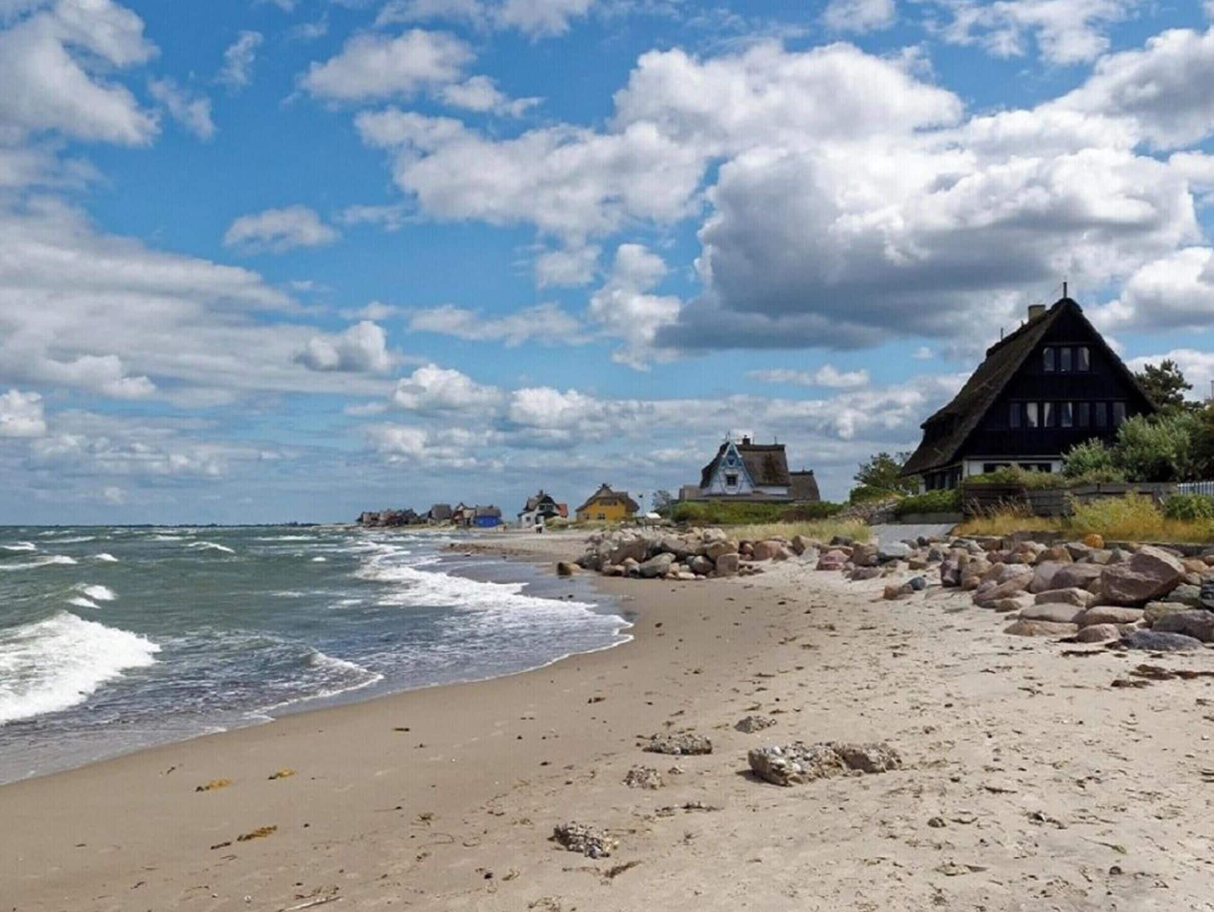 Ein Strand mit felsigem Ufer und traditionellen Häusern.
