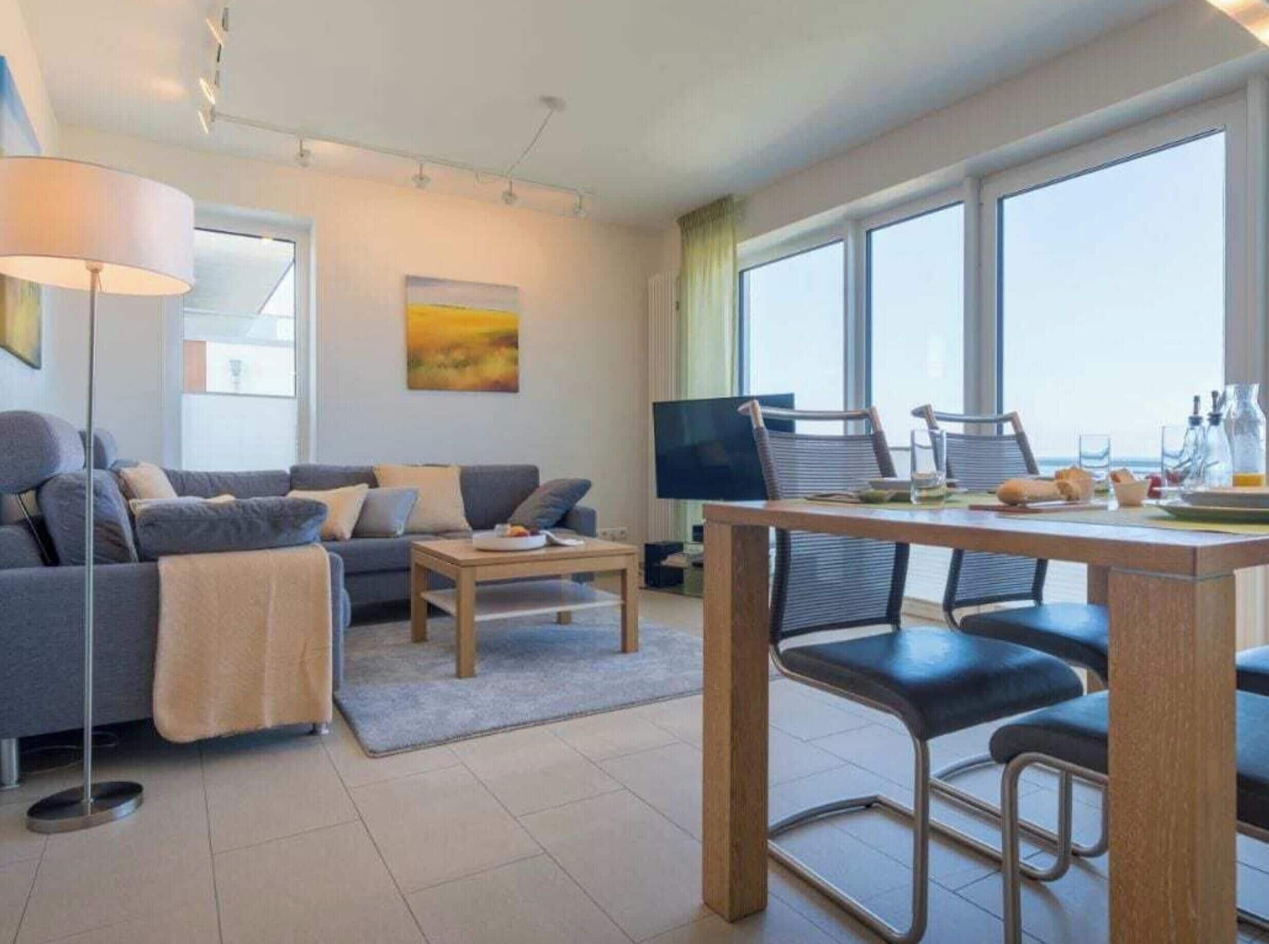 Ein modernes Wohnzimmer mit Sofa, Couchtisch und Essbereich mit Stühlen.