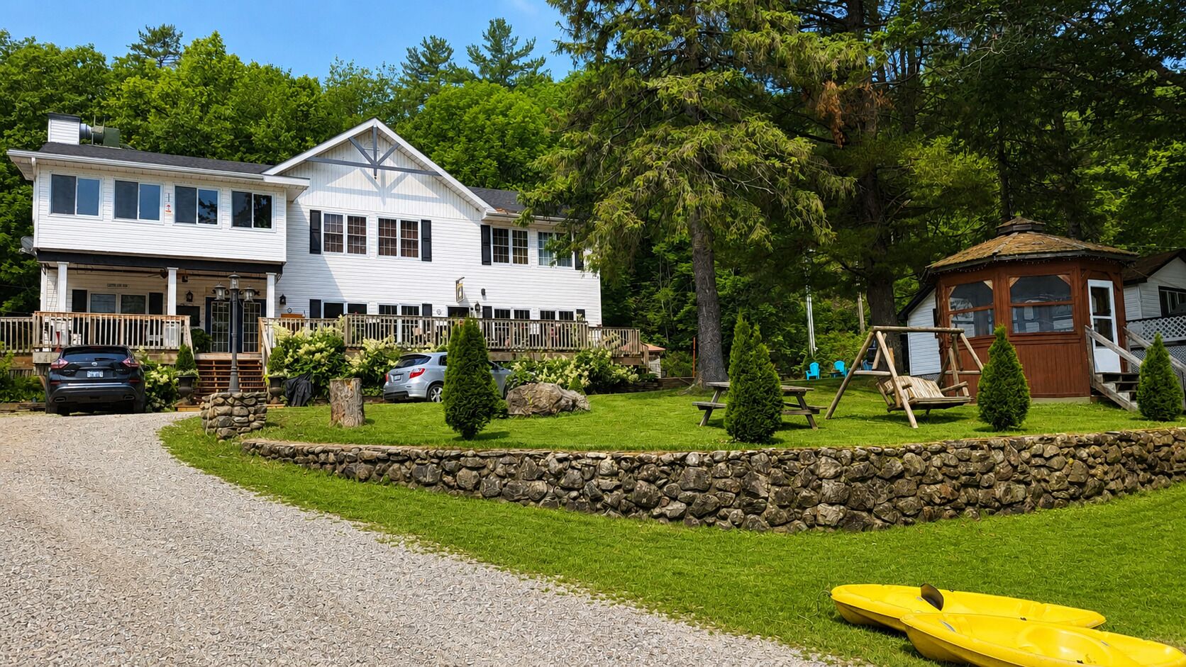 A two-story building with a stone retaining wall, a picnic area, and a swing set.