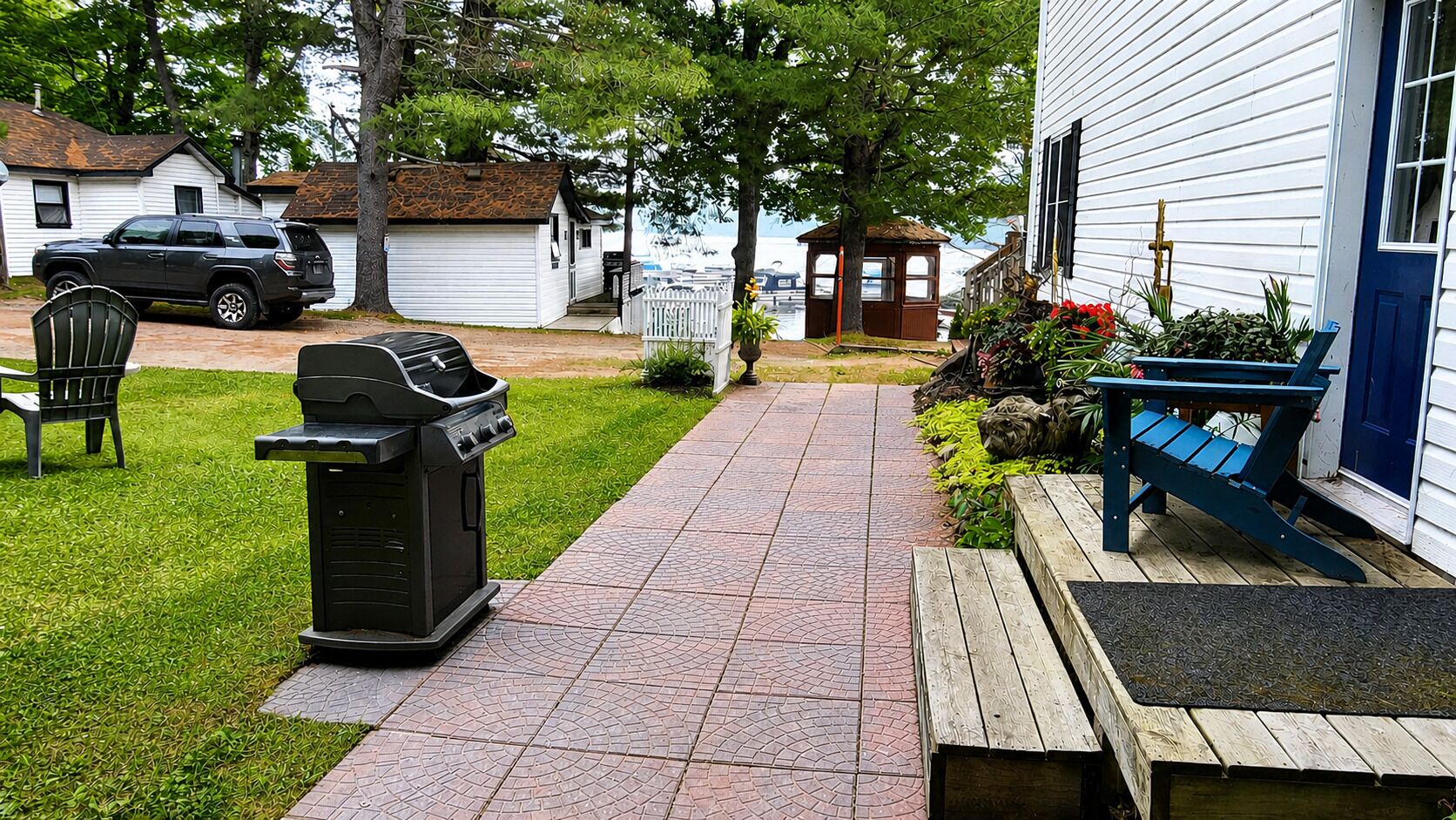 A pathway leading to a house with a barbecue grill, a bench, and a small shed.