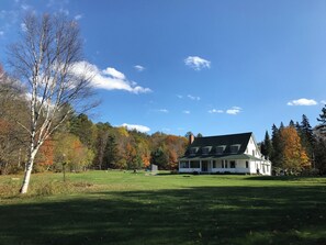 A large white house with a green roof, surrounded by a grassy field and trees with autumn foliage. - Main Cottage of historic Muskoka resort Clyffe House.  Very spacious 5 bedroom (Port Sydney)