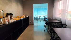 Una cocina moderna con una barra alargada, un espacio para café y vistas a un área de estar exterior a través de un ventanal.