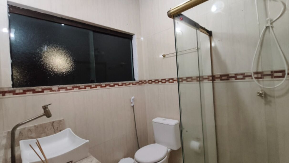 A bathroom with a glass-enclosed shower, a white sink, and a toilet.