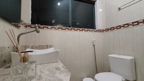 Une salle de bain avec une baignoire, des toilettes et une fenêtre.
