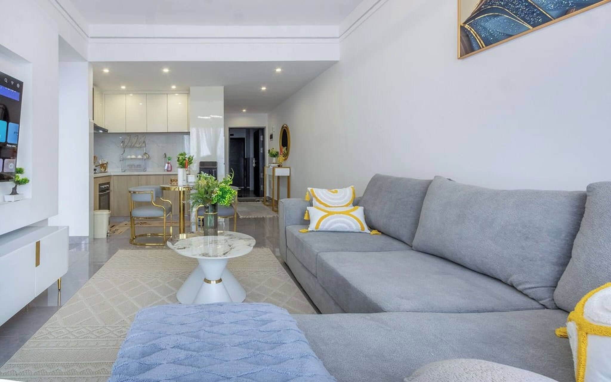 A modern living room with a grey sofa, a coffee table, and a blue ottoman.