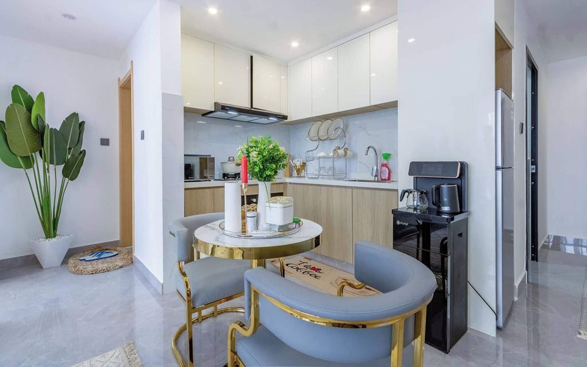 Una cocina moderna con armarios blancos, una cafetera y un comedor con dos sillas y una mesa.