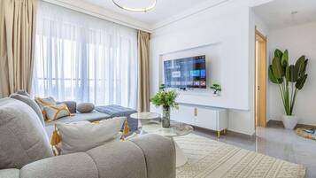 Ein modernes Wohnzimmer mit einer Couch, einem wandmontierten Flachbildfernseher und einer Topfpflanze.