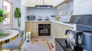 A modern kitchen with a microwave, oven, and coffee maker. There is a small trash bin and a coffee-themed placemat on the floor. - Nairobi City -kilimani Next to Junction Mall (Nairobi)
