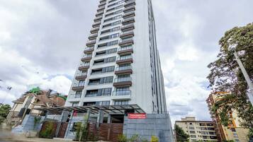 Un immeuble résidentiel à plusieurs étages, doté de balcons, d’une entrée sécurisée et d’un panneau indiquant les appartements disponibles à la vente.