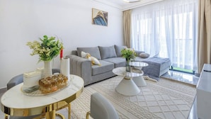 A modern living room with a grey sofa, a round coffee table, and a dining table with a vase of flowers. - Nairobi City -kilimani Next to Junction Mall (Nairobi)