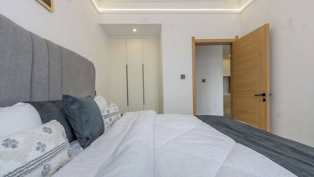 A bedroom with a bed, a wardrobe, and a door leading to another room. - Nairobi City -kilimani Next to Junction Mall (Nairobi)