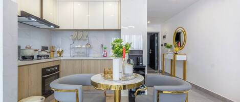 Une cuisine moderne avec des meubles blancs, un coin repas comprenant deux chaises et une table, et un miroir accroché au mur.
