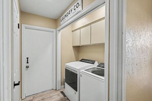 A laundry room with a door, a washing machine, and a dryer. - Prairie Meets Desert Modern 3BR Near OU (Norman)