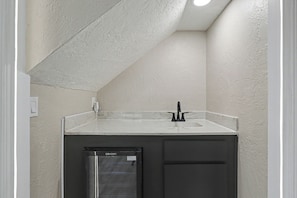 A compact bathroom with a white countertop, a black sink, and a built-in dishwasher. - Prairie Meets Desert Modern 3BR Near OU (Norman)