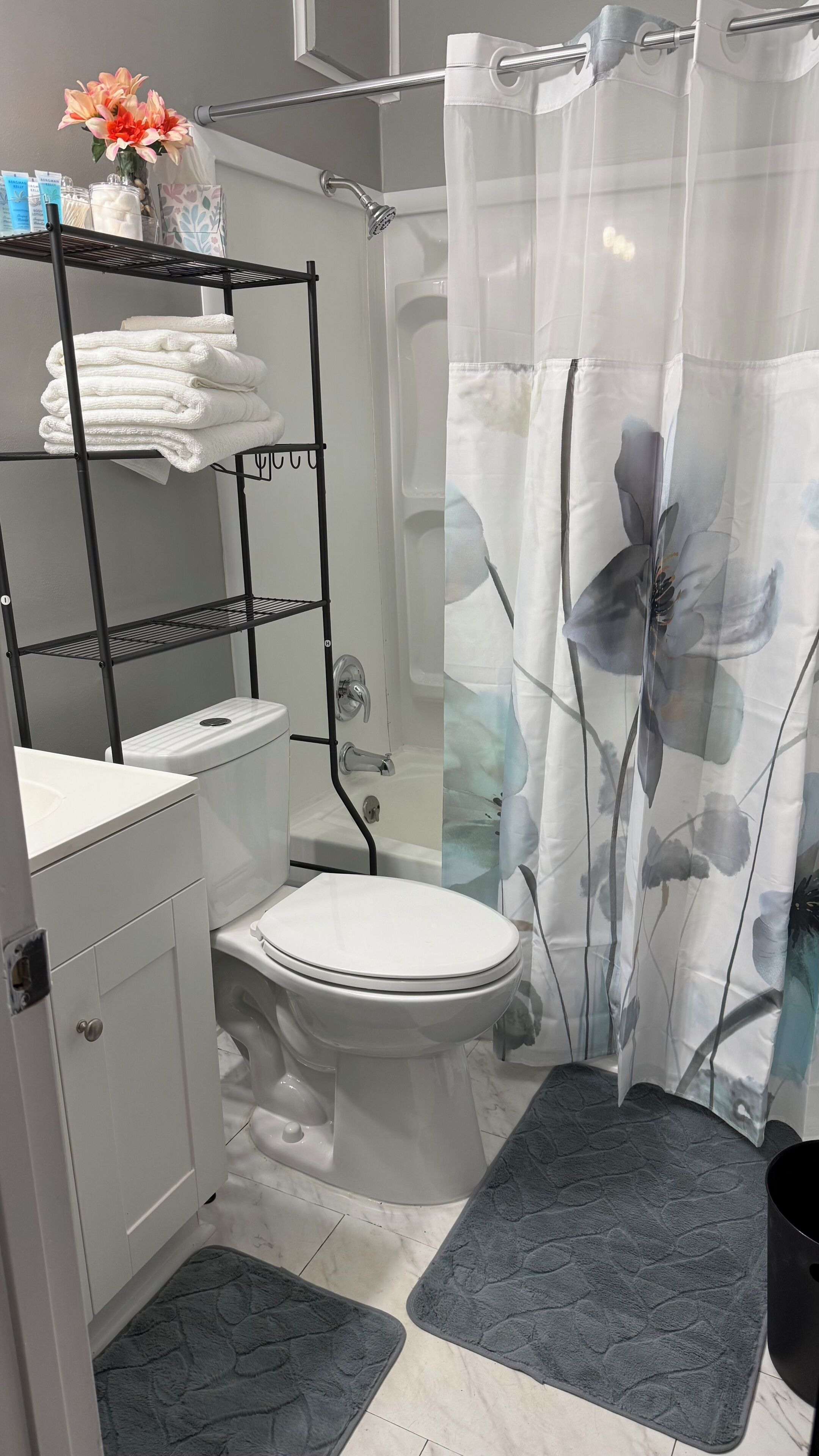 Een badkamer met toilet, douche, wastafel, handdoekhouder en douchegordijn.