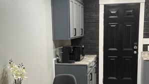 Eine moderne Küche mit grauen Schränken, einer schwarzen Tür und einem Holzespeisetisch mit Stühlen.